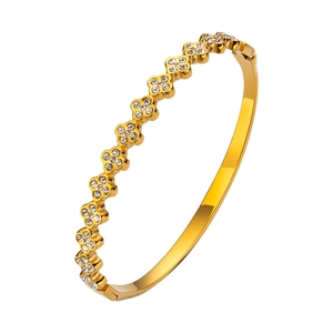 Brazalete de acero de titanio dorado con motivos de trébol de cuatro hojas y circonas