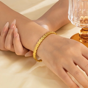 Primo piano del bracciale a cuore con quadrifoglio dorato e motivi floreali traforati