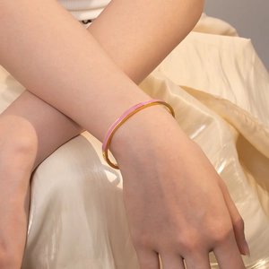 Detailansicht eines vergoldeten Edelstahl-Armreifs mit rosa Emaille am Handgelenk