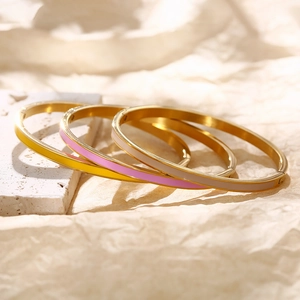 Detail von drei schmalen 18k vergoldeten Emaille-Armreifen in Gelb, Rosa und Beige