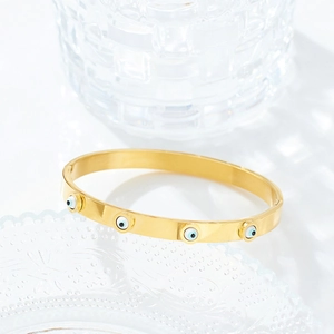 Detailed shot of gold-plated stainless steel cuff featuring four blue evil eye charms