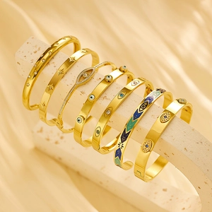 Close-up of seven gold-plated bangles featuring evil eye and star patterns with zircon