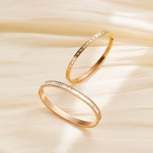 Detail of rose gold bangle with baguette cut cubic zirconia on champagne satin background