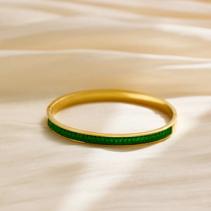 Detail of gold-plated stainless steel bangle with emerald-cut green cubic zirconia