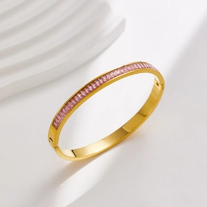 Close-up of gold-plated stainless steel bangle with channel-set pink rectangular zircons