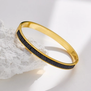 Detail of gold-plated stainless steel bracelet featuring black rectangular stone inlay