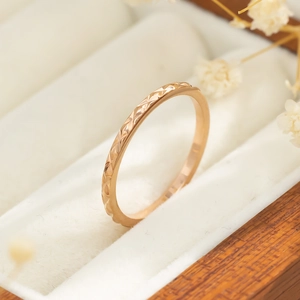 Detail van roségouden titaniumstalen ring met geometrische textuur op fluwelen basis
