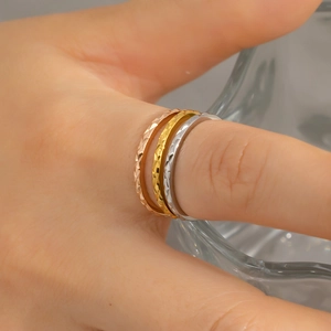 Close-up of three-piece stackable diamond-cut rings in gold, rose gold and silver