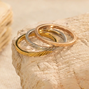 Close-up van goud, zilver en roségoud stapelbare ringen met getextureerd oppervlak