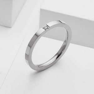 Macro view of minimalist silver stainless steel ring featuring a single inset round diamond