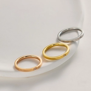 Detailed trio of minimalist titanium rings in gold, silver, and rose gold with tiny diamonds