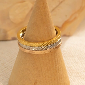 Detailopname van minimalistische gestapelde ringen in goud, zilver en roségoud met gravure