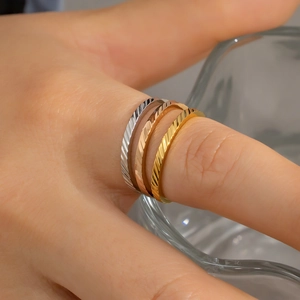 Detail van stapelbare ringen in goud, zilver en roségoud met gegraveerde diamanttextuur