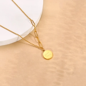 Detail of 18k gold plated necklace with asymmetric chain and Good Luck engraved pendant