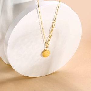 Detail of 18k gold plated titanium necklace featuring a Good Luck engraved round pendant