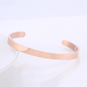 Detail of minimalist rose gold C-shaped cuff bracelet with a polished mirror finish surface