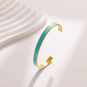 Macro detail of the gold stainless steel bangle featuring sky blue enamel inlay design