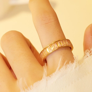 Gros plan d'une bague dorée avec zircons roses taille baguette sur le doigt