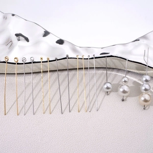 Macro shot of assorted gold and silver eye pins shown with beaded pearl jewelry crafts