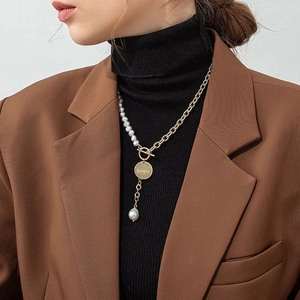 Detail of a pearl and gold chain necklace with hope coin and baroque pearl pendant