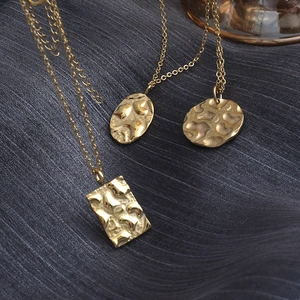 Detail view of 18K gold plated titanium necklaces with geometric hammered texture pendants