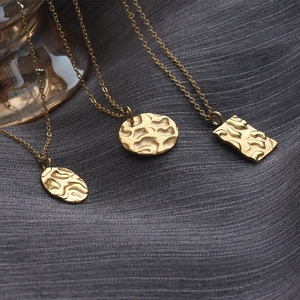 Three gold hammered geometric necklaces with oval, round, and rectangular pendants