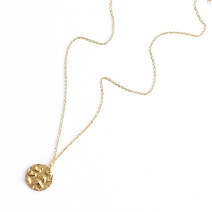 Detailed macro of 18K gold plated titanium round pendant with handcrafted hammer texture