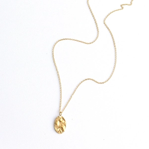 Detail view of the gold titanium steel necklace showing the irregular hammered oval pendant