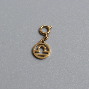 Detailed macro view of a gold-plated Libra zodiac sign pendant with a spring clasp