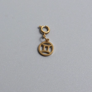 Macro detail of gold plated stainless steel Gemini zodiac disc charm with spring clasp
