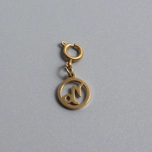 Macro detail of a gold Capricorn zodiac pendant with a spring clasp on a grey background