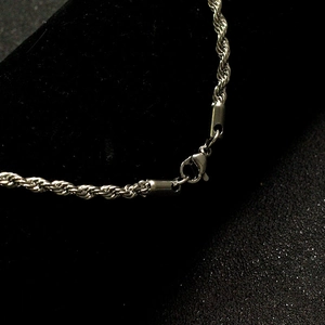 Close-up of silver twist rope chain with lobster clasp on black velvet background
