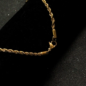 Detailed close-up of a gold rope chain necklace featuring a secure lobster clasp closure