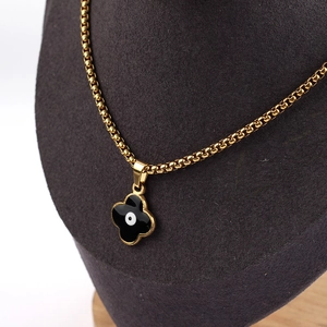 Detail of clover pendant with evil eye motif on a golden square pearl chain