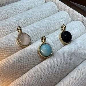 Détail de pendentifs dorés sertis de pierres roses, bleues et noires brillantes