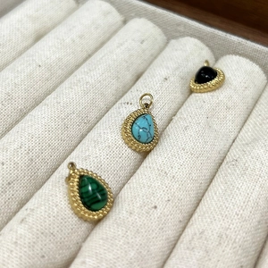 Détail de pendentifs en pierres précieuses en forme de goutte avec bordure perlée dorée