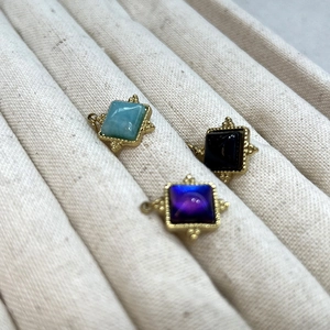 Détail de pendentifs carrés en or avec pierres bleues et noires sur présentoir