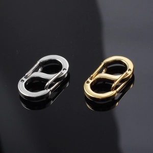 Close-up of gold and silver S-shaped stainless steel spring buckles on black reflective surface
