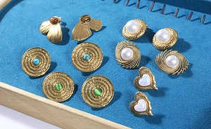 Detail of vintage gold earrings featuring pearls and turquoise on a blue velvet background