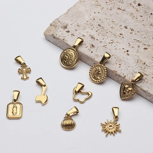 Retro gold Roman coin cross and butterfly charms on minimalist textured stone background