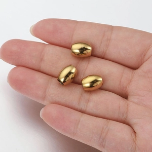 Detailed view of three polished gold barrel beads held in hand for jewelry DIY