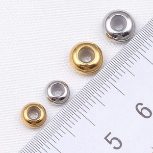 Dettaglio macro di perle distanziatrici in acciaio lucido oro e argento con scala