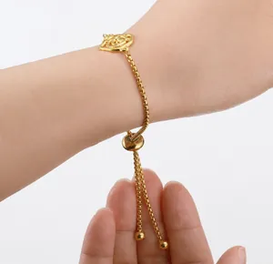 Detail of golden adjustable box chain bracelet with rose pattern sliding charm on wrist