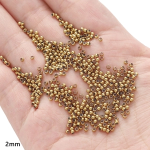 Macro shot of 2mm gold stainless steel spacer beads on palm for DIY jewelry making
