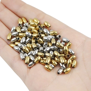 Detailed view of gold and silver oval stainless steel beads held in hand for DIY jewelry