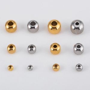 Macro shot of gold and silver textured stainless steel grid spacer beads in three sizes
