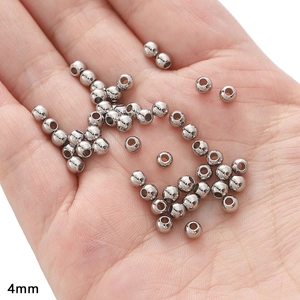 Macro shot of 4mm silver stainless steel beads on palm for DIY jewelry making