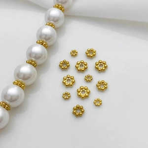 Dettaglio di distanziatori in metallo dorato a fiore su una collana di perle chic