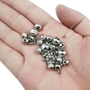 Macro shot of stainless steel spacer beads with grid texture and polished finish in palm