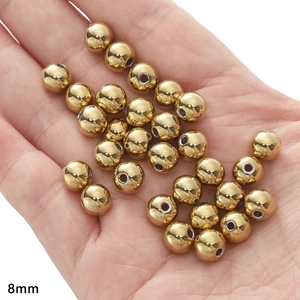 Macro shot of 8mm gold hollow metal beads for jewelry making held in a palm